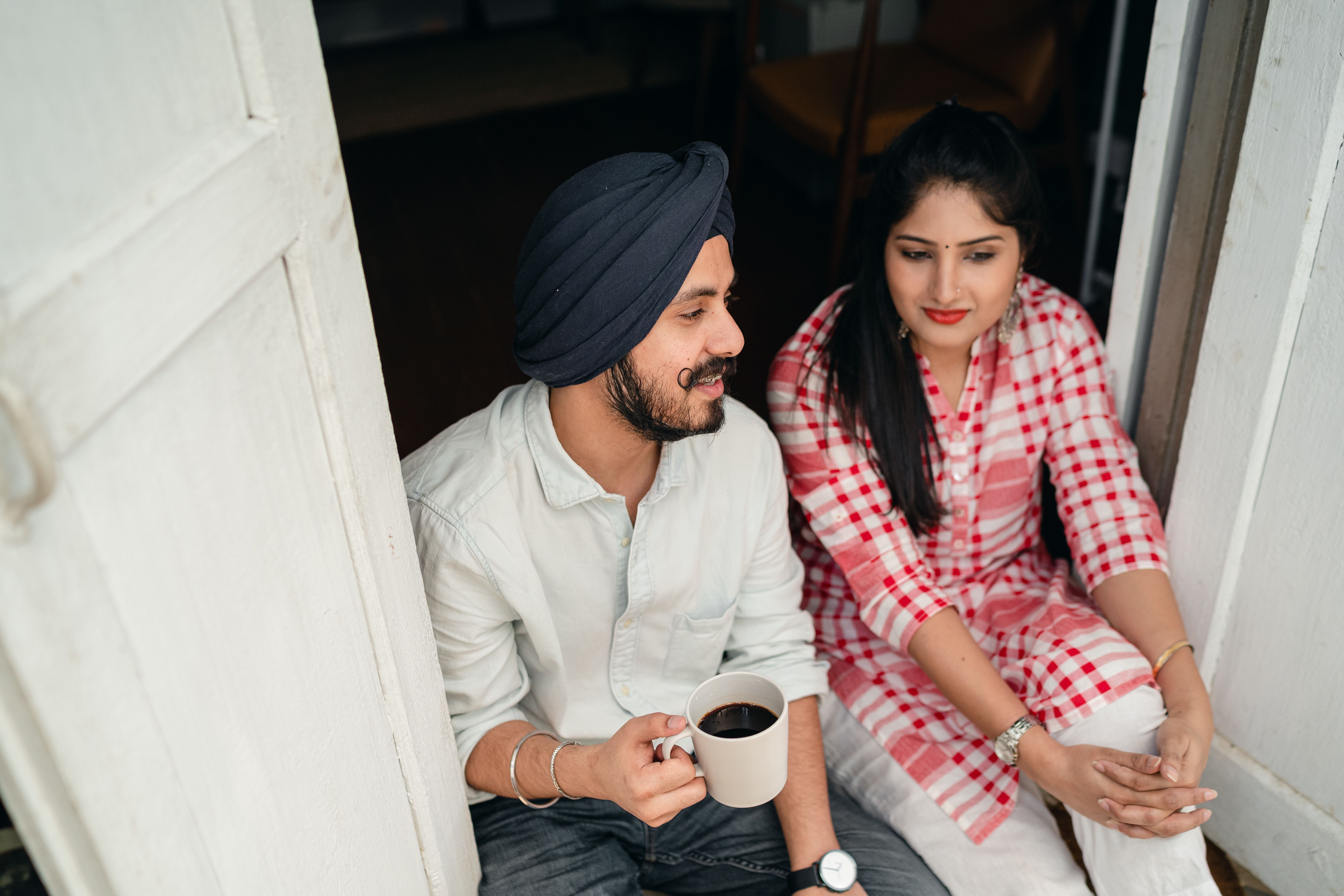 Two people talking over coffee in a doorway.