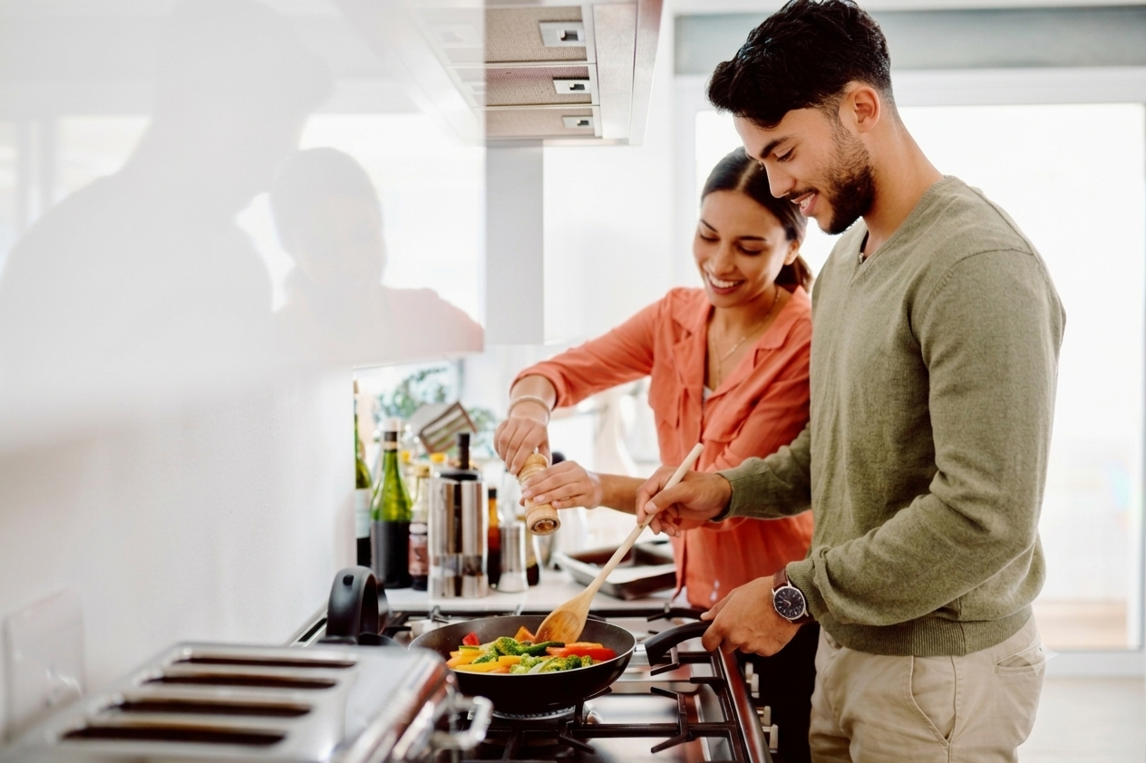 A couple cooking together in a bright kitchen.