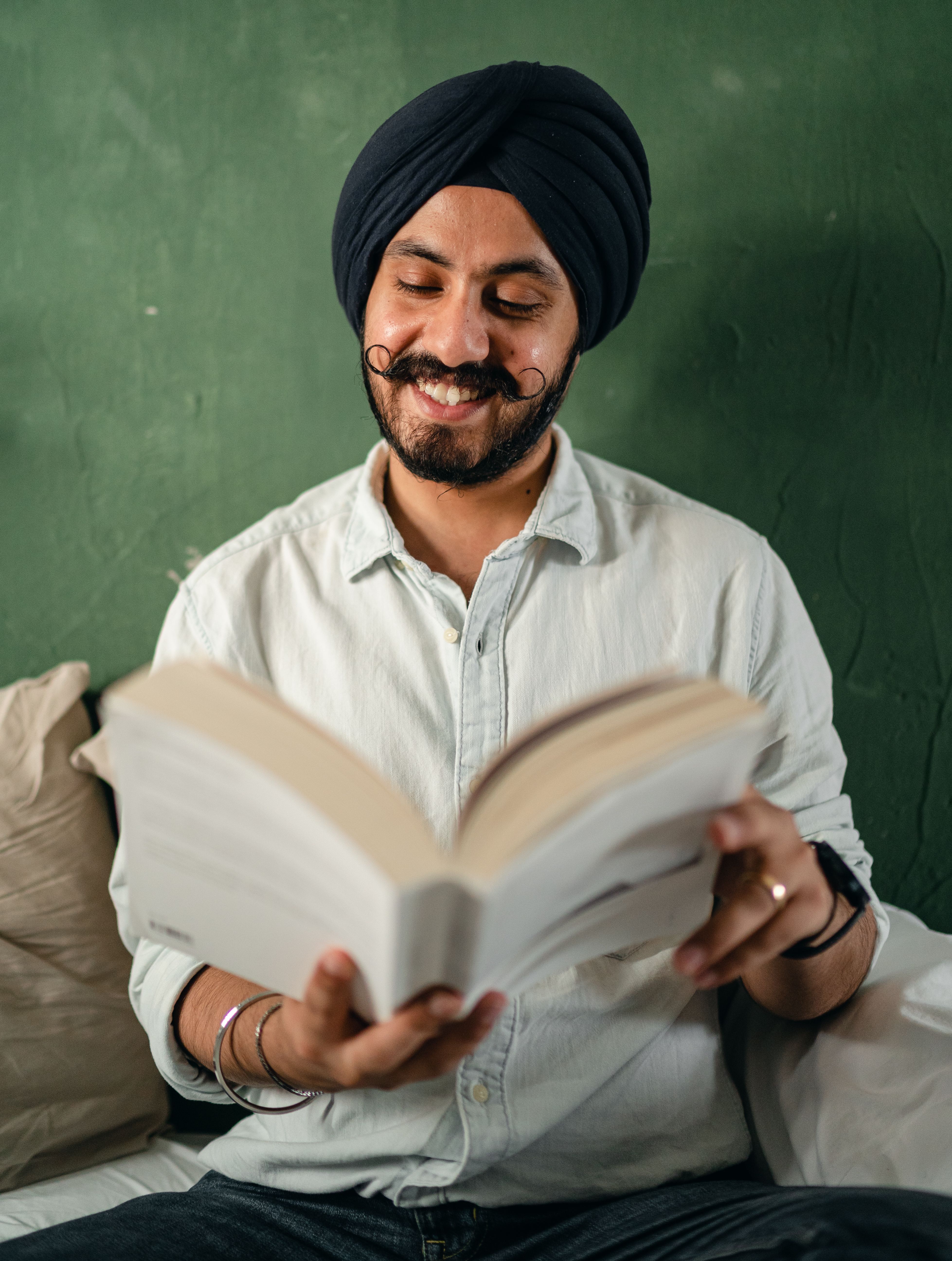Reading a book, smiling, at home.